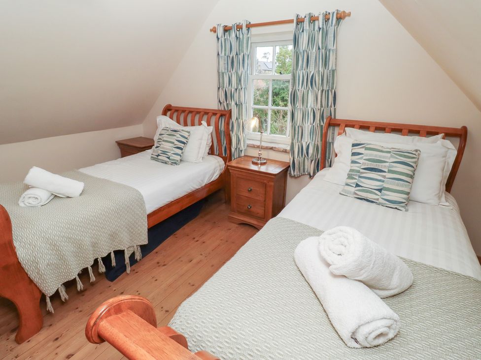 A bedroom with two beds and a window at The Poachers Pocket in Whittingham near Powburn