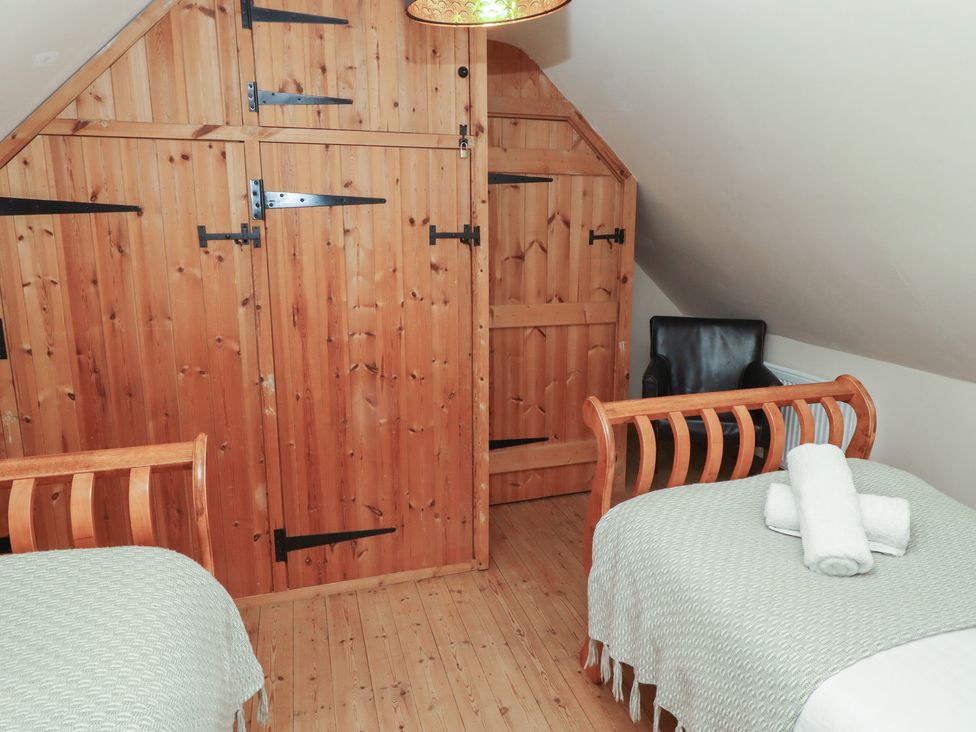A bedroom with two beds and a wardrobe at The Poachers Pocket in Whittingham near Powburn