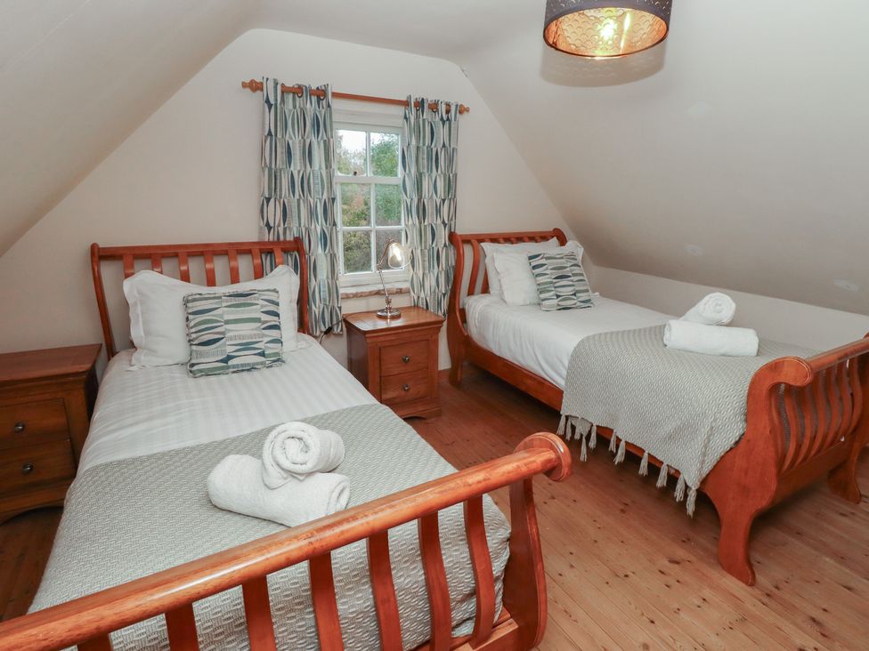 A bedroom with two beds and bedside tables at The Poachers Pocket in Whittingham near Powburn