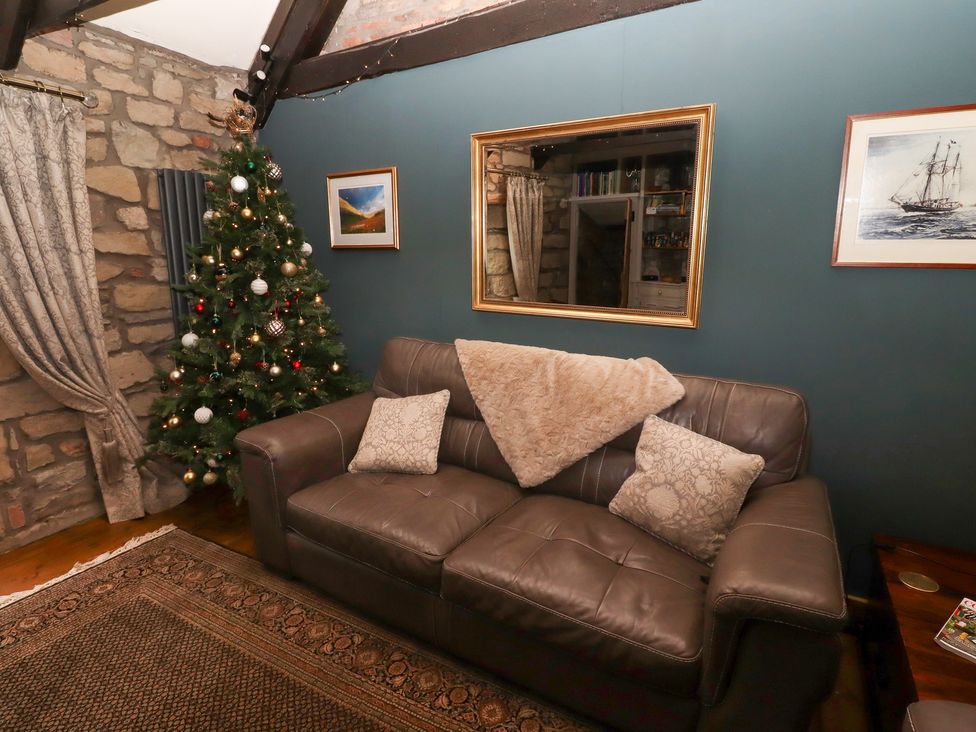 A living room with a sofa and a Christmas tree at The Poachers Pocket in Whittingham near Powburn