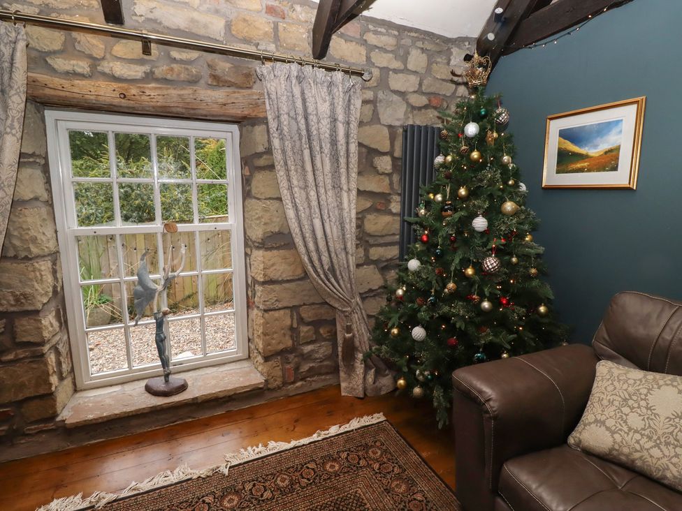 A living room with a Christmas tree and a window at The Poachers Pocket in Whittingham near Powburn
