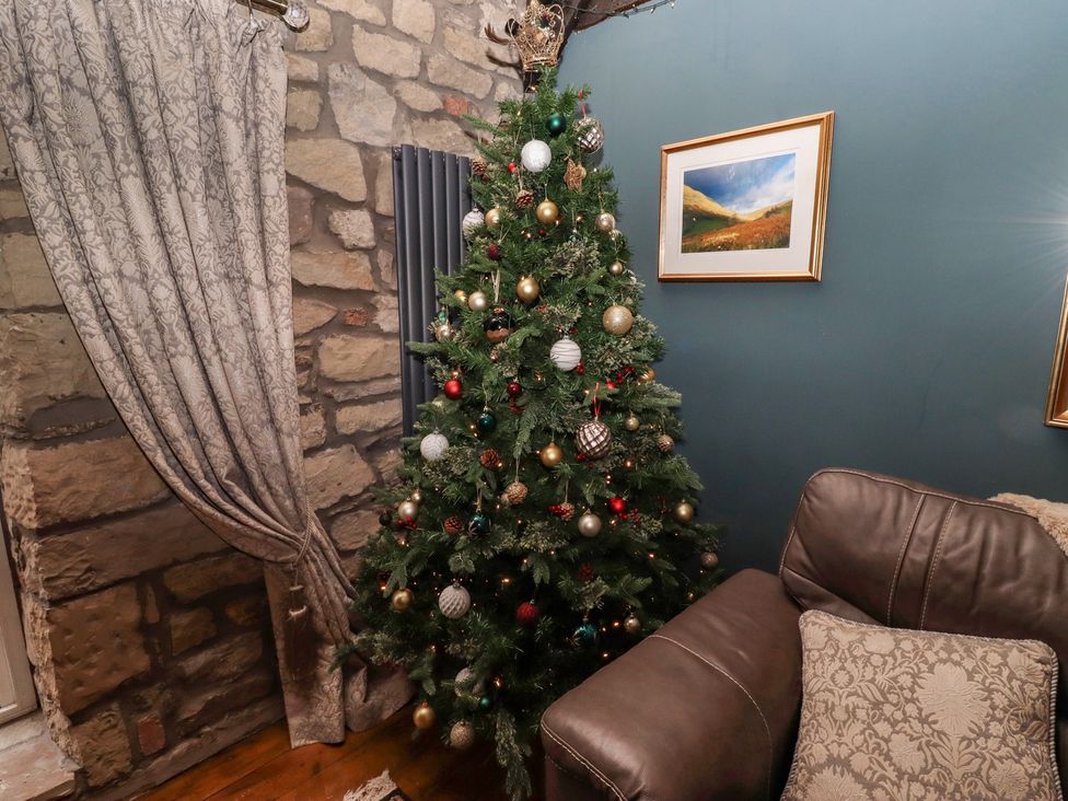 A living room with a Christmas tree and sofa at The Poachers Pocket in Whittingham near Powburn