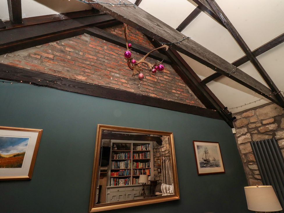 A living room with bookshelves and a mirror at The Poachers Pocket in Whittingham near Powburn