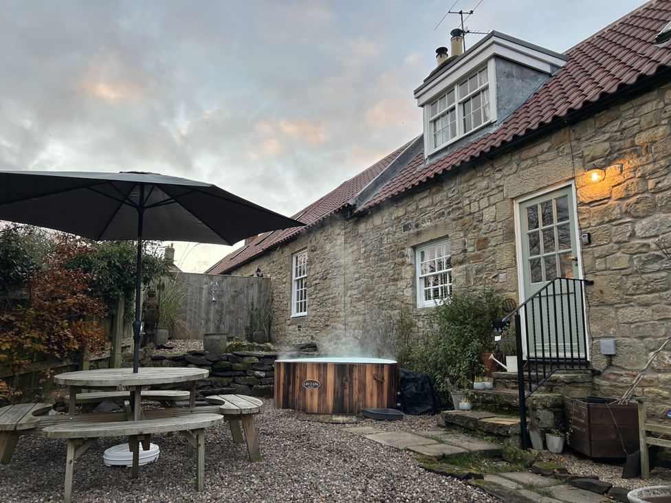 A garden with a hot tub and outdoor table at The Poachers Pocket in Whittingham near Alnwick