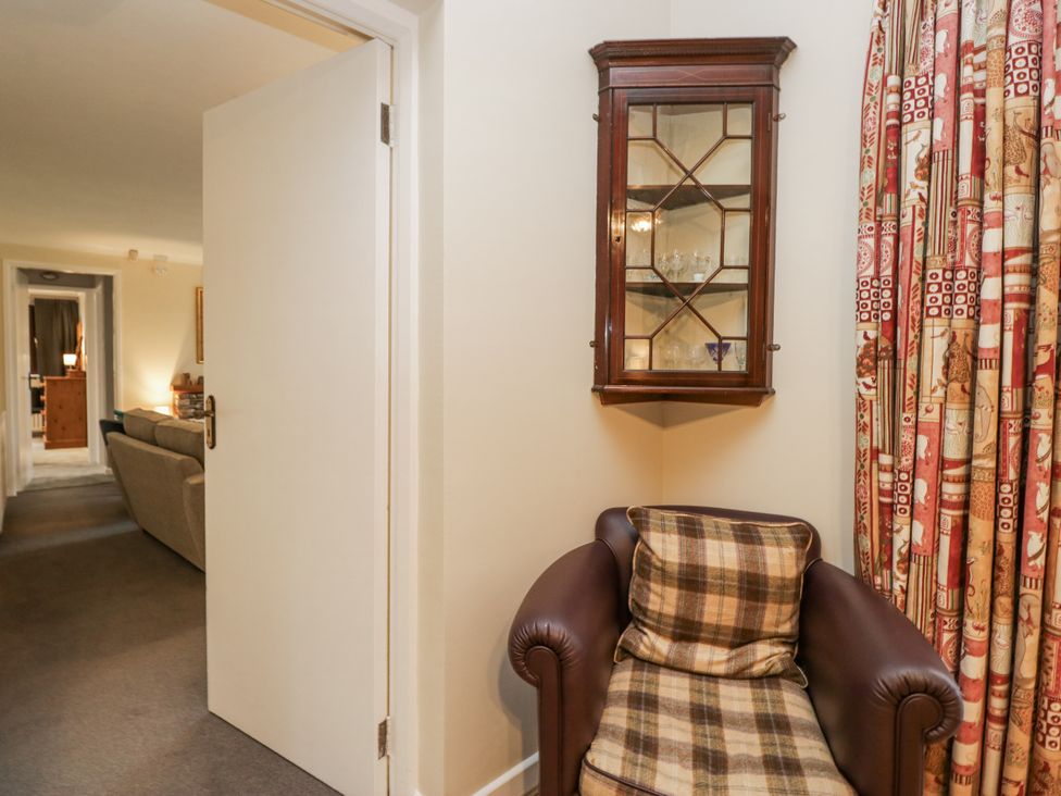 A hallway with an armchair and wall cabinet at Beech Brae in Kendal