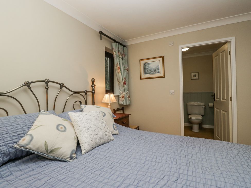 A bedroom with a bed and a door leading to a bathroom at Beech Brae in Kendal