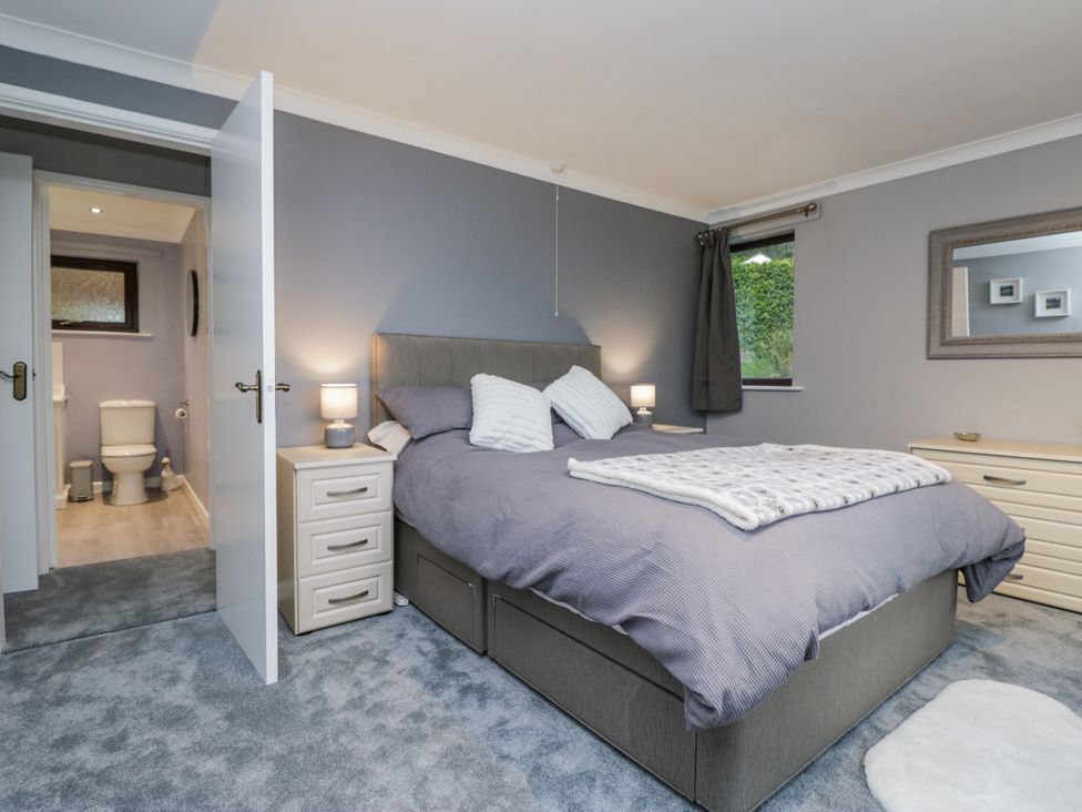 A bedroom featuring a bed and a doorway leading to a bathroom at Beech Brae in Kendal