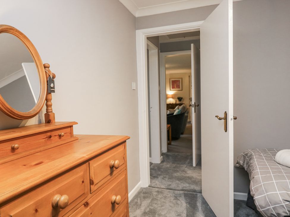 A bedroom with a dresser and door leading to another room at Beech Brae in Kendal