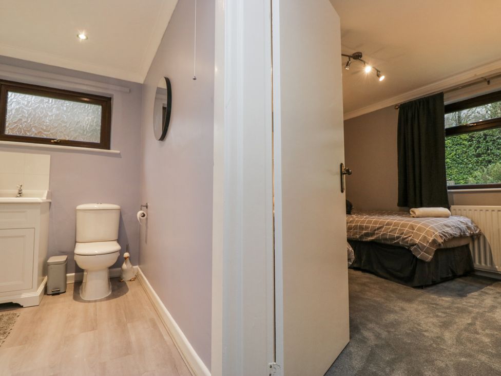 A bathroom with a toilet and sink adjoining a bedroom at Beech Brae Kendal