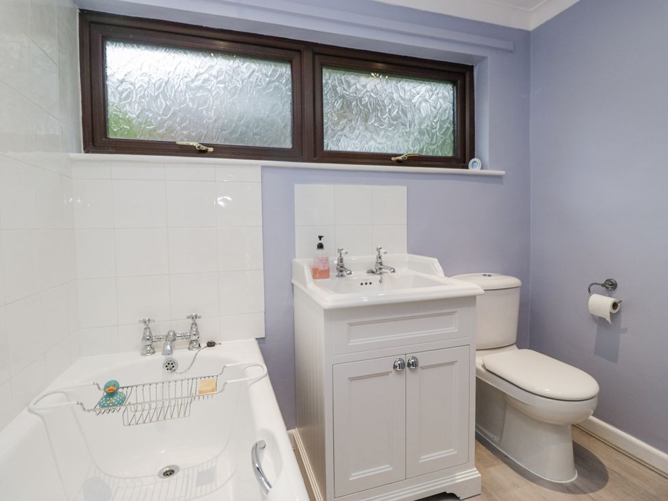 A bathroom with a bath tub, sink, and toilet at Beech Brae Kendal