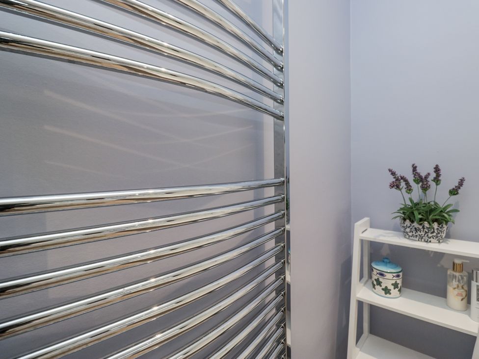 A towel radiator and shelf with decorative items at Beech Brae Kendal