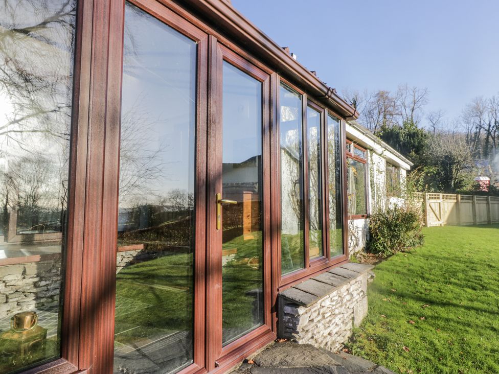 A conservatory with glass doors and a view of the garden at Beech Brae in Kendal