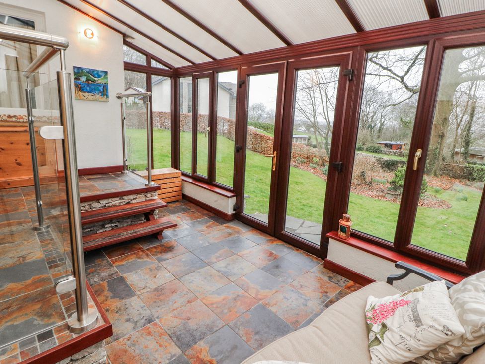 A conservatory with a staircase and glass doors at Beech Brae in Levens