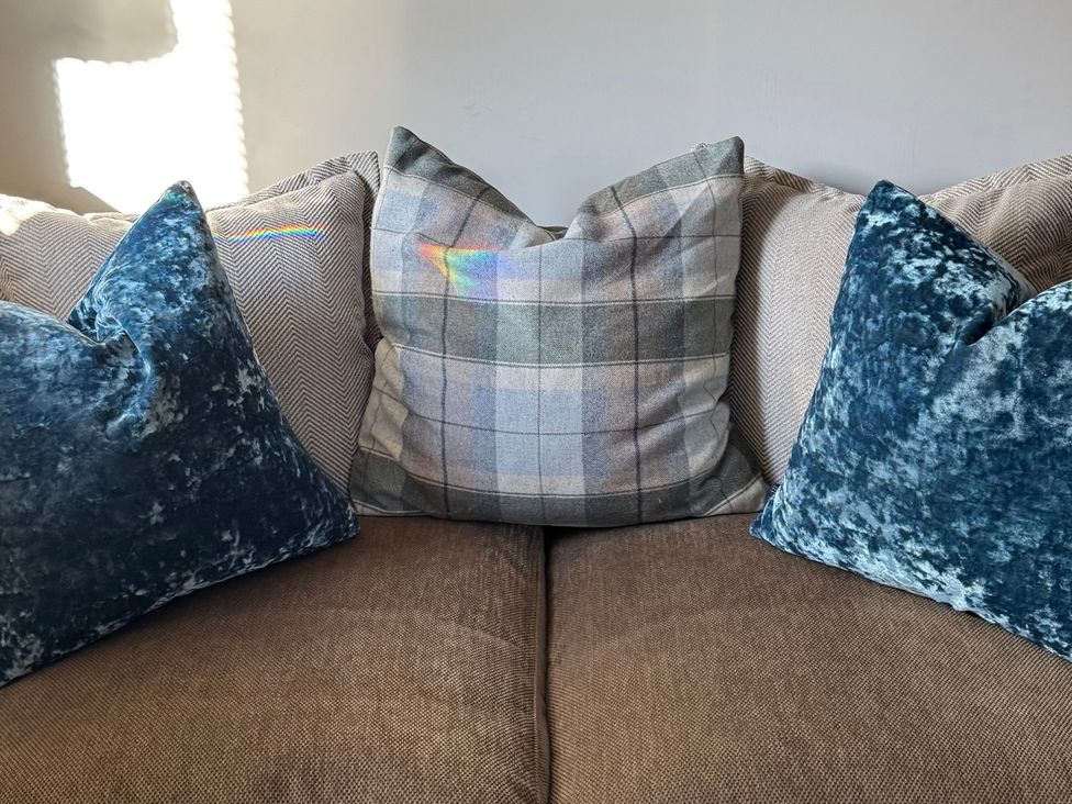A couch with pillows in a living room at Johns Cottage in Harrogate