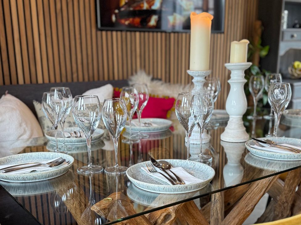 A dining table set with glasses and plates at Johns Cottage in Harrogate
