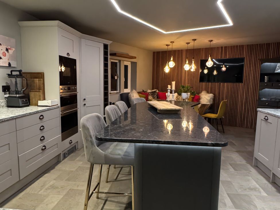A kitchen with an island and bar stools at Johns Cottage in Harrogate