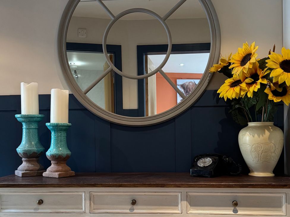An entrance hall with a mirror and flowers at Johns Cottage in Harrogate