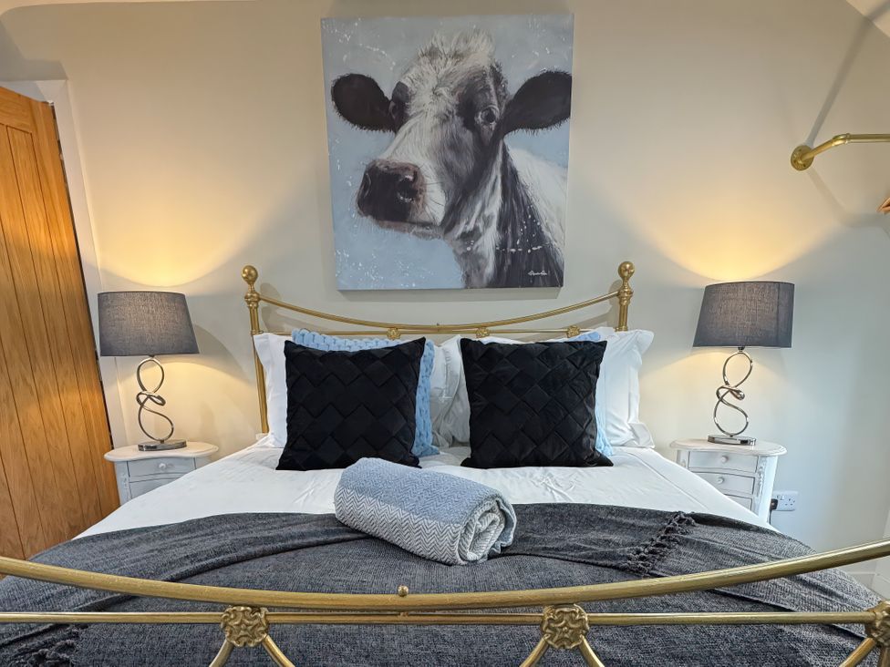 A bedroom featuring a bed with pillows and wall art at Johns Cottage in Harrogate
