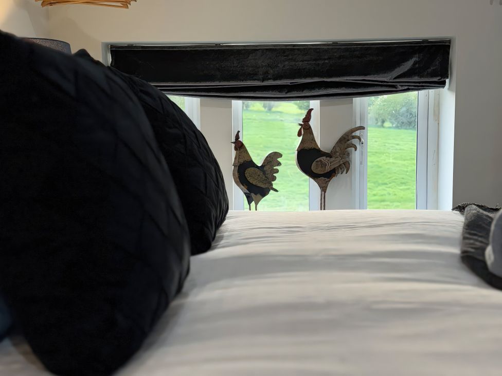 A bedroom with pillows on the bed and chickens by the window at Johns Cottage in Harrogate