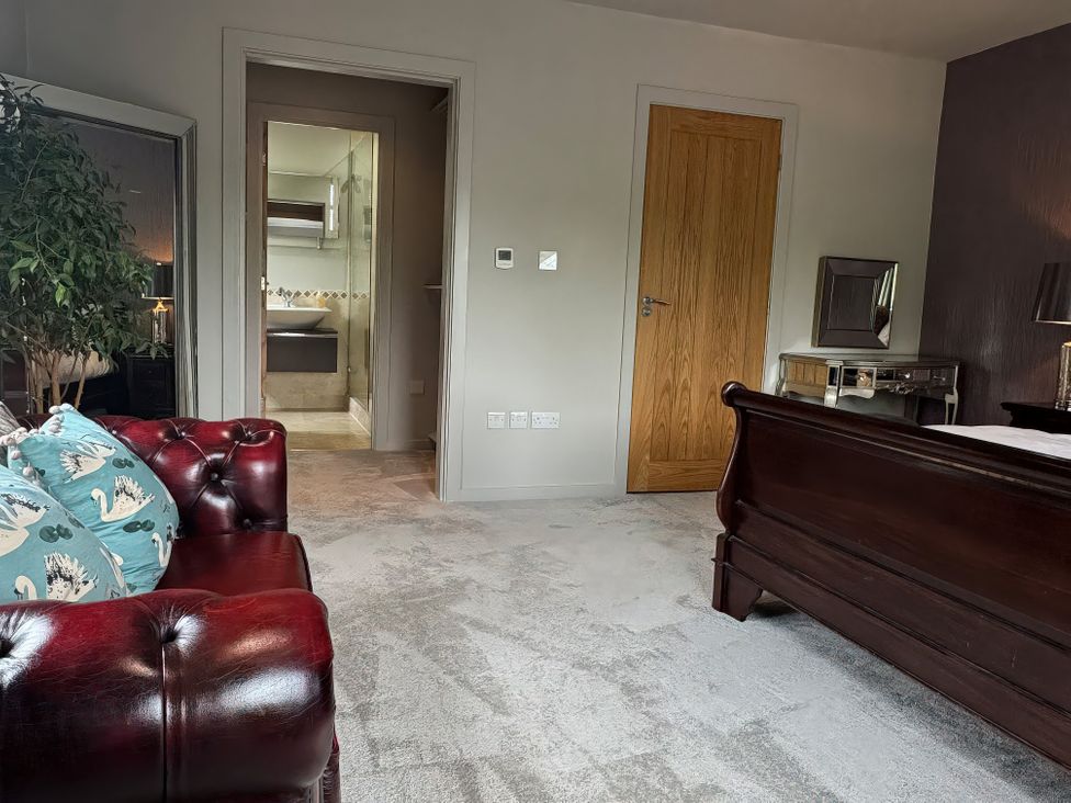 A bedroom with a bed, sofa and door leading to a bathroom at Johns Cottage in Harrogate