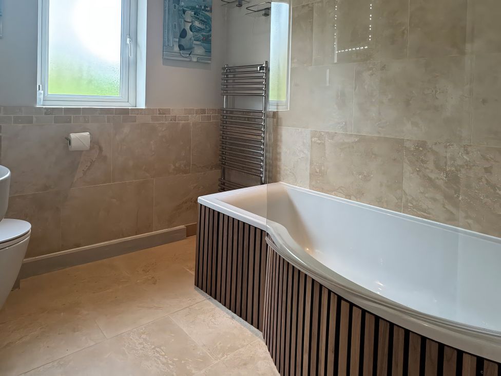 A bathroom with a bathtub and toilet at Johns Cottage in Harrogate