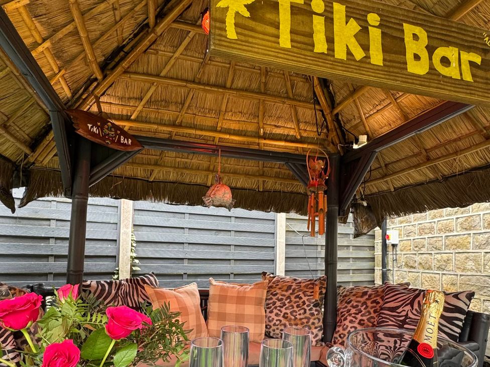 A tiki bar with cushions and champagne on the table at Johns Cottage Harrogate
