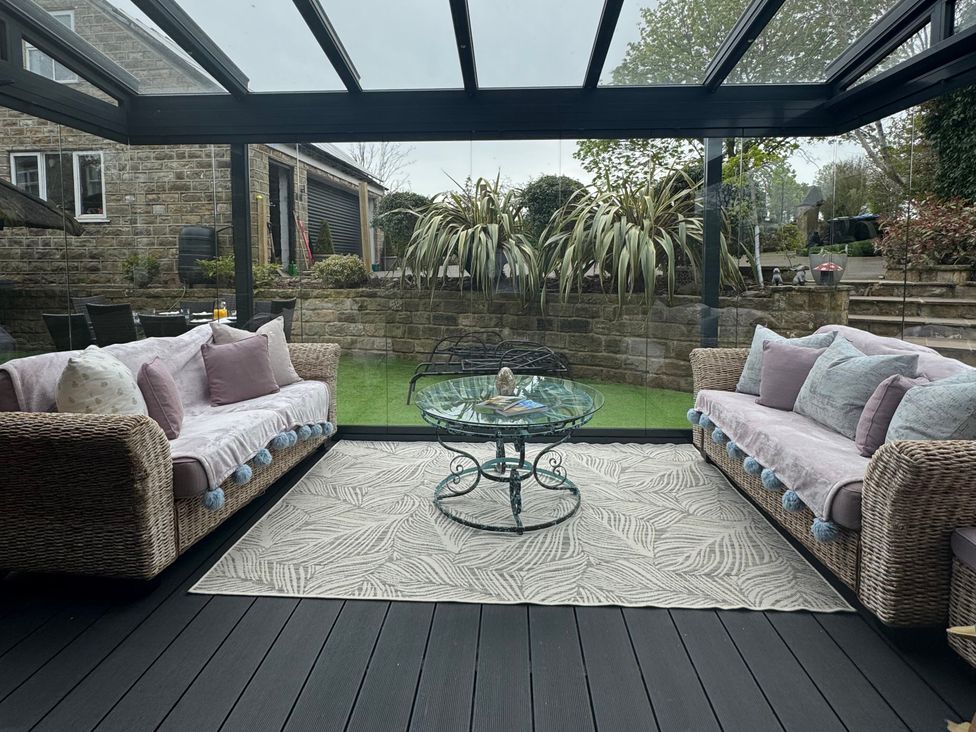 A conservatory with sofas and a table at Johns Cottage in Harrogate