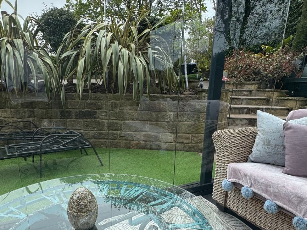 A conservatory with a table and outdoor furniture at Johns Cottage in Harrogate