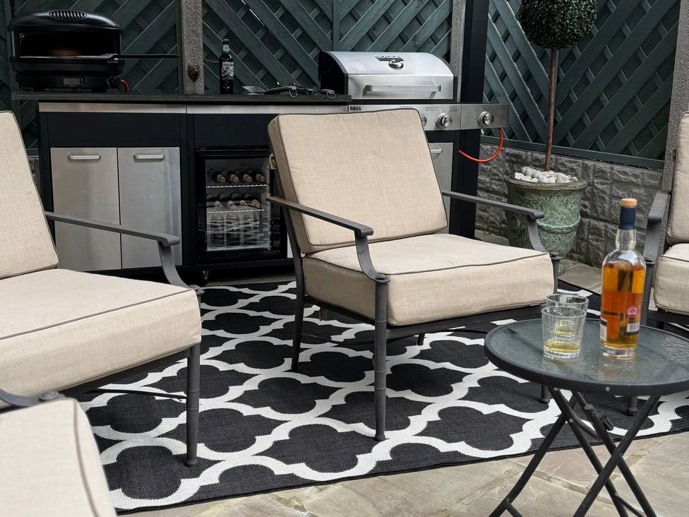 An outdoor patio with chairs and a barbecue grill at Johns Cottage in Harrogate