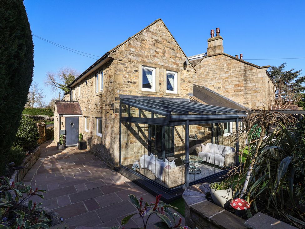 A conservatory attached to a house in the garden at Johns Cottage in Hampsthwaite
