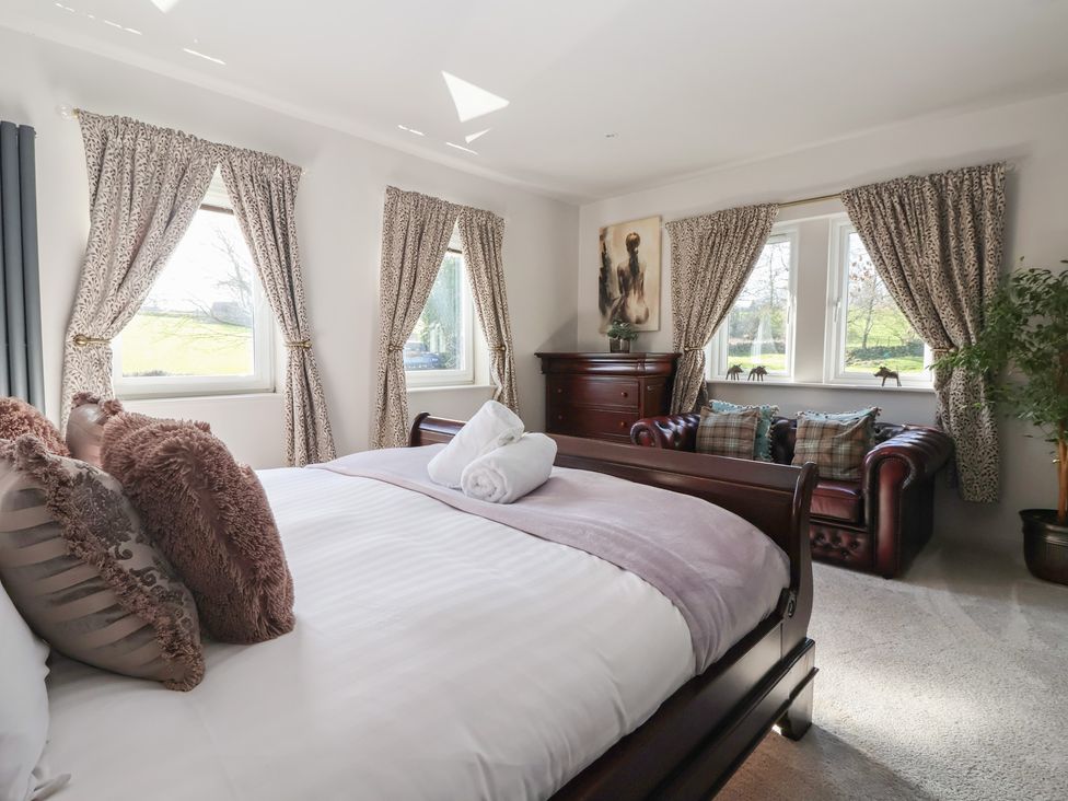 A bedroom with a bed and armchair at Johns Cottage in Hampsthwaite