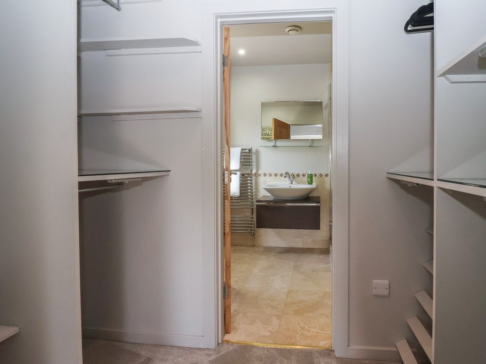 A wardrobe leading to a bathroom with a sink and towel rack at Johns Cottage Hampsthwaite