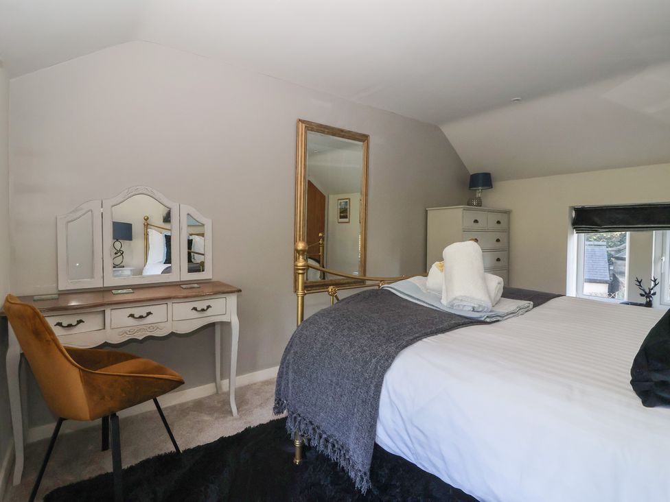 A bedroom with a bed and dressing table at Johns Cottage in Hampsthwaite