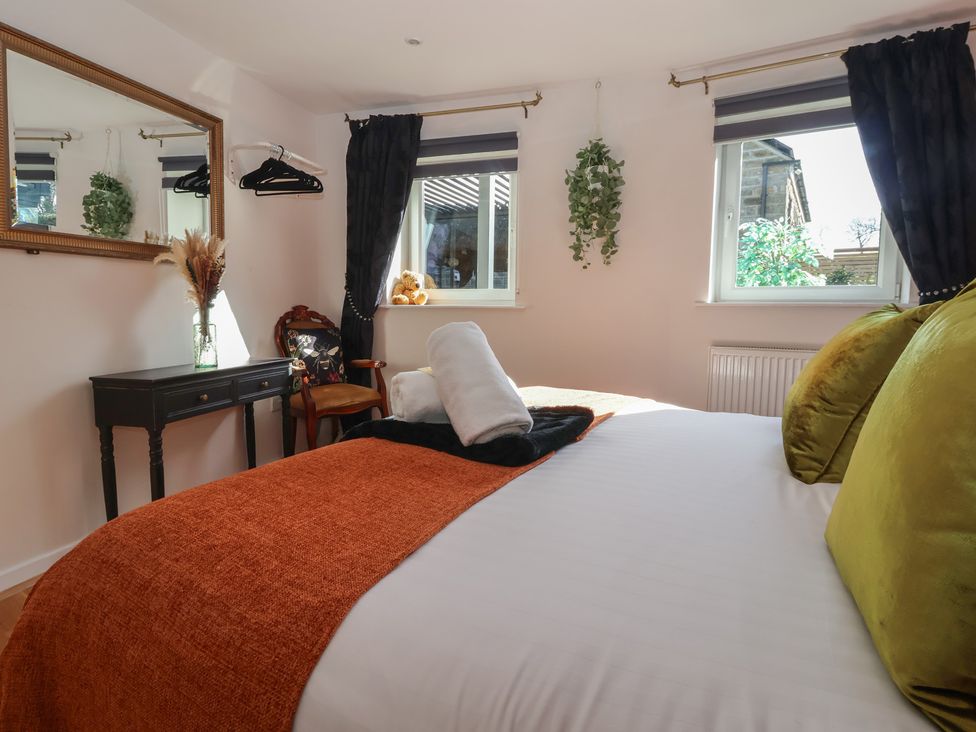 A bedroom with a bed and a mirror at Johns Cottage in Hampsthwaite