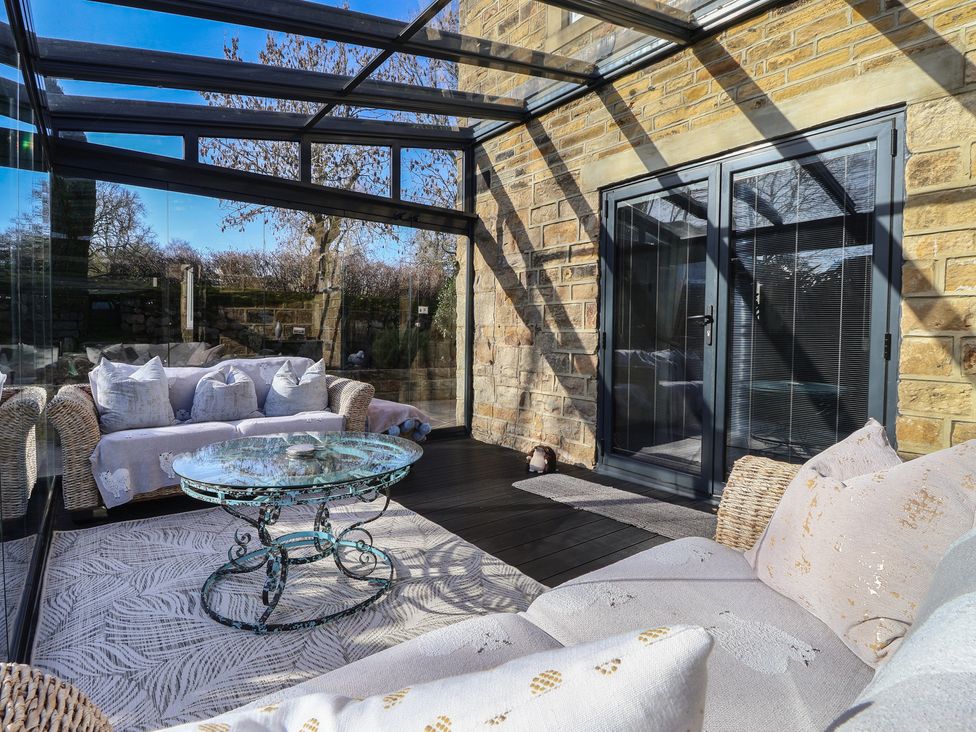 A conservatory with a glass door and seating at Johns Cottage in Hampsthwaite