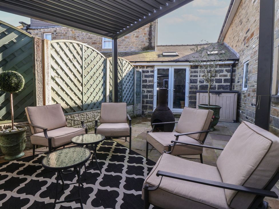 An outdoor patio area with seating and a chiminea at Johns Cottage in Hampsthwaite