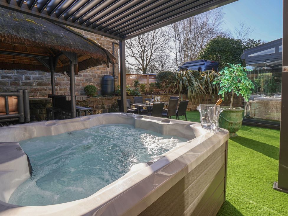 A garden with a hot tub and outdoor seating at Johns Cottage in Hampsthwaite