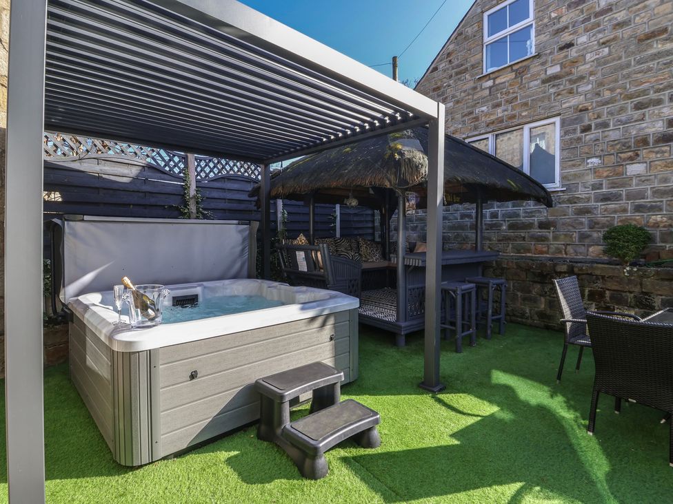 A garden with a hot tub and seating area at Johns Cottage in Hampsthwaite