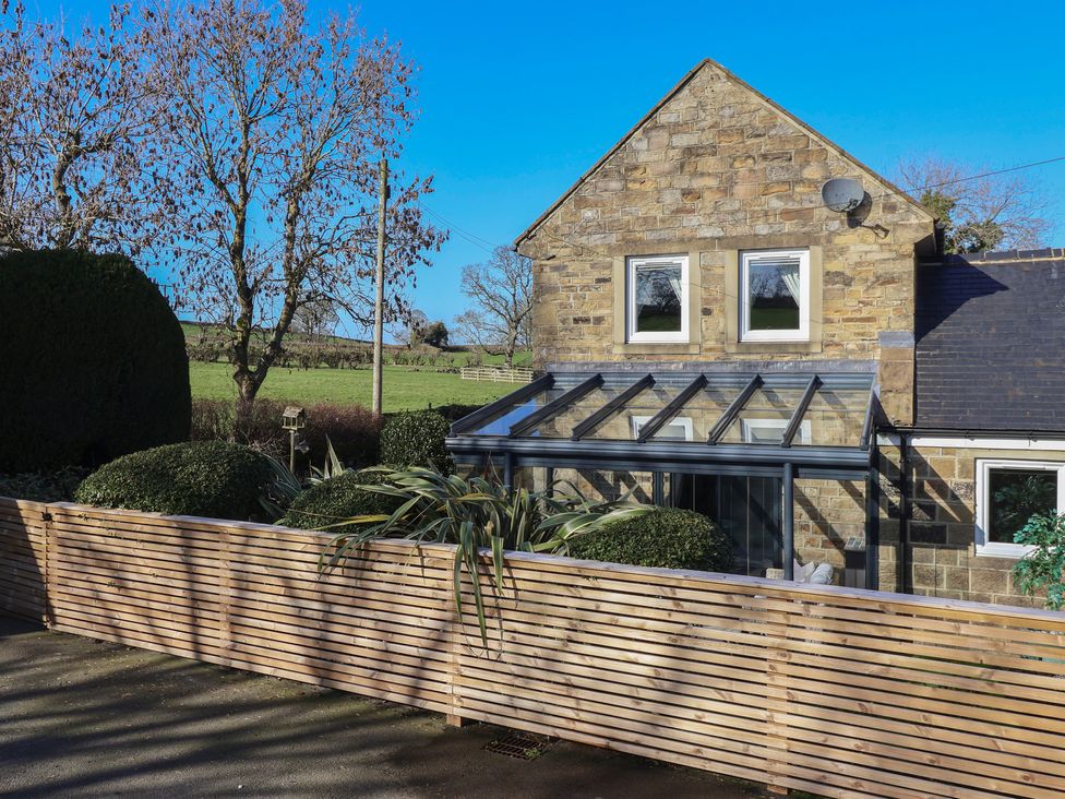 A house with conservatory and trees at Johns Cottage in Hampsthwaite