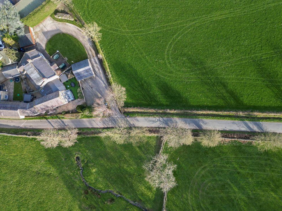 An aerial view of a house next to a road and greenery at Johns Cottage in Hampsthwaite