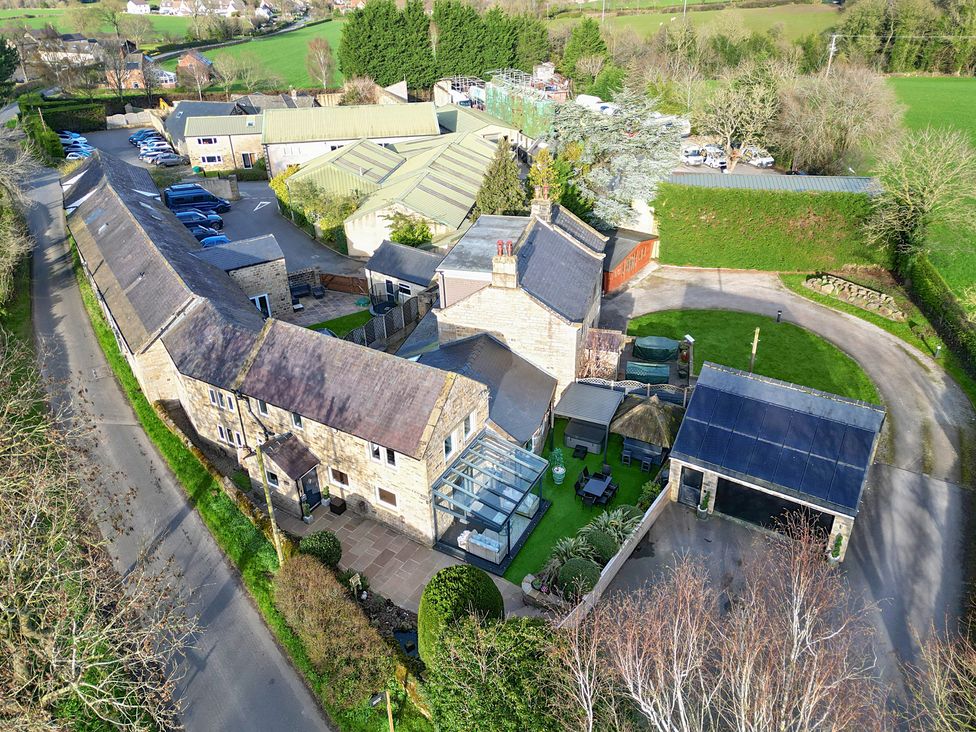 An outdoor view of multiple buildings and cars at Johns Cottage in Hampsthwaite