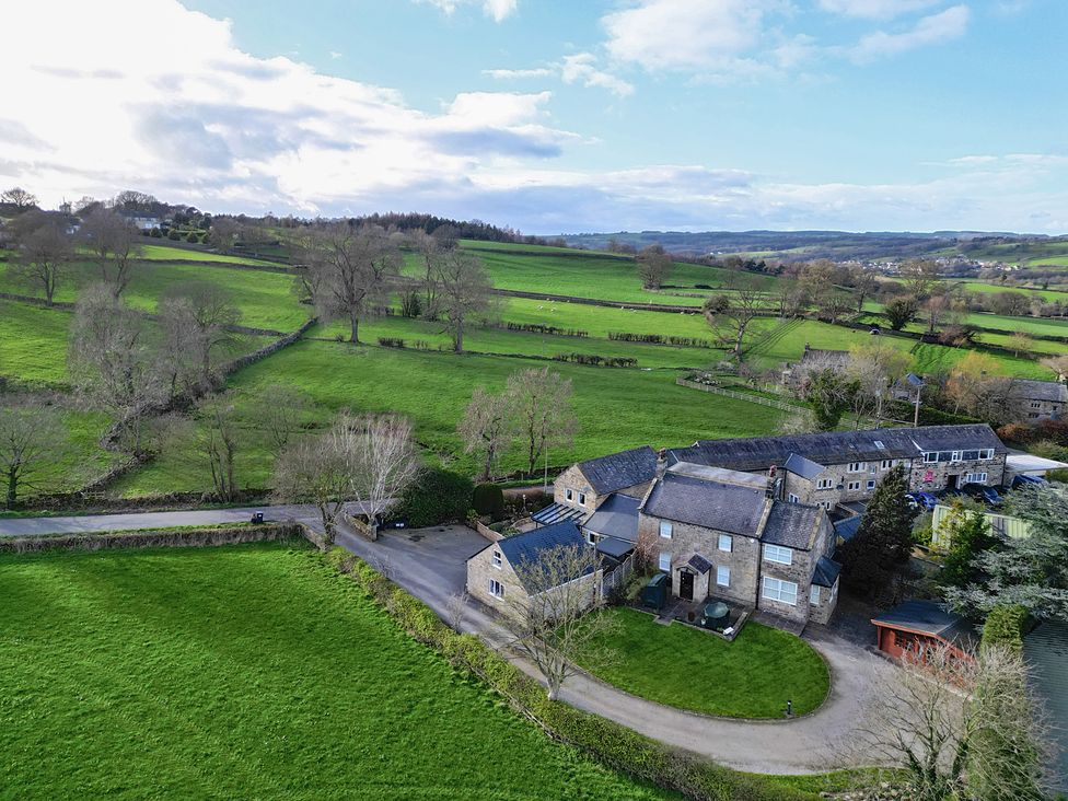 An aerial view of a farmstead with fields and trees at Johns Cottage in Hampsthwaite