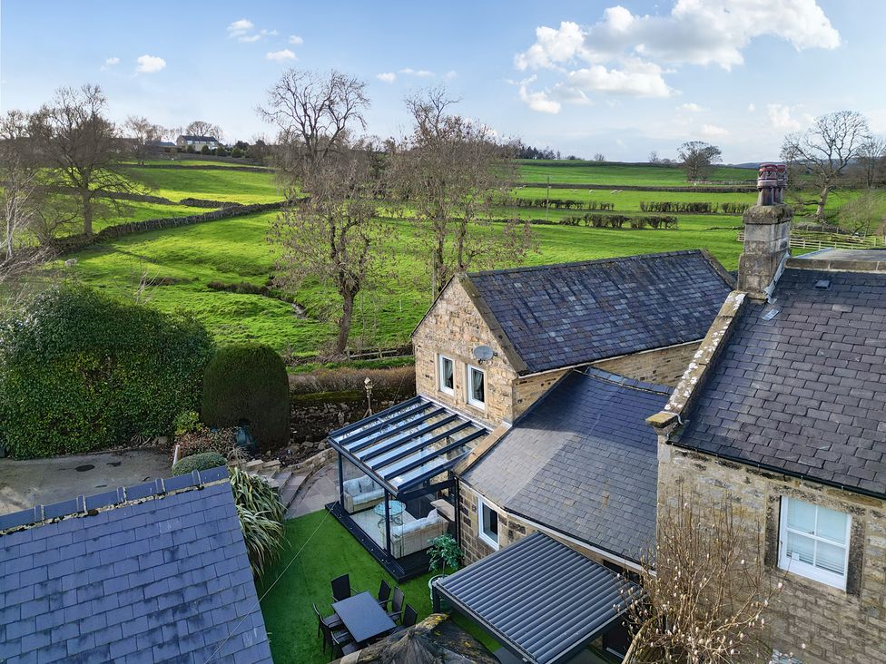 A view of a house with a glass extension and green fields at Johns Cottage Hampsthwaite