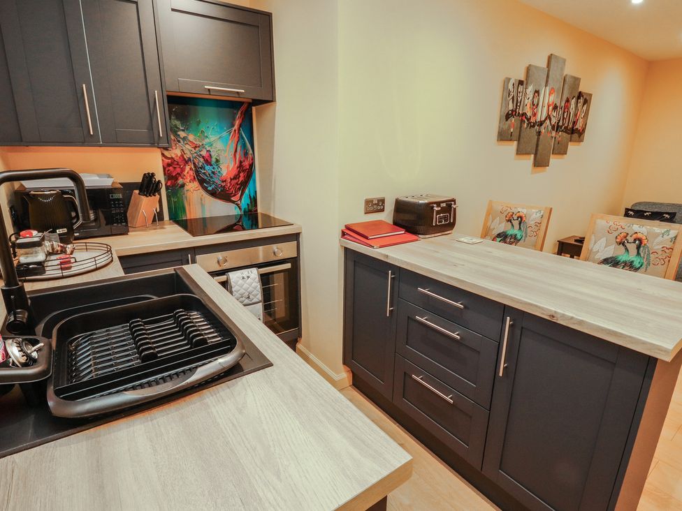 A kitchen with cabinets oven sink and dining chairs at The Nook 