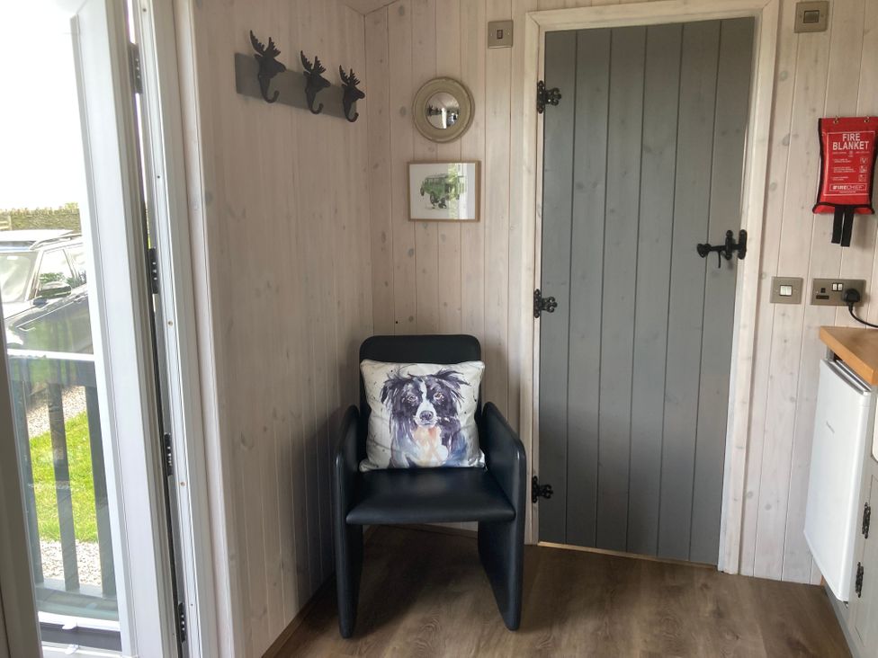 An entryway with an armchair and hooks at Little Acre in Oxenhope