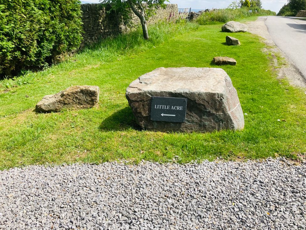 A sign for Little Acre with rocks and grass at Little Acre in Oxenhope