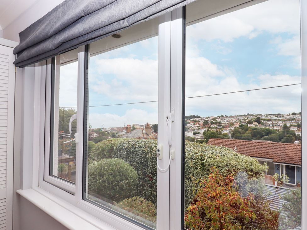 A window with a view of houses and bushes at 15 Summerland Avenue Dawlish