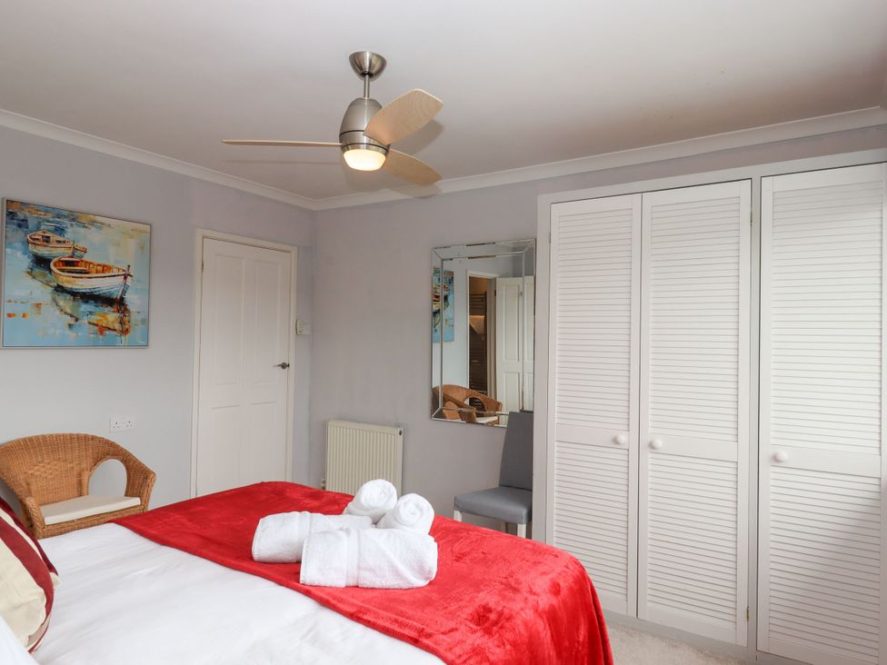 A bedroom with a bed, towels, and wall art at 15 Summerland Avenue Dawlish