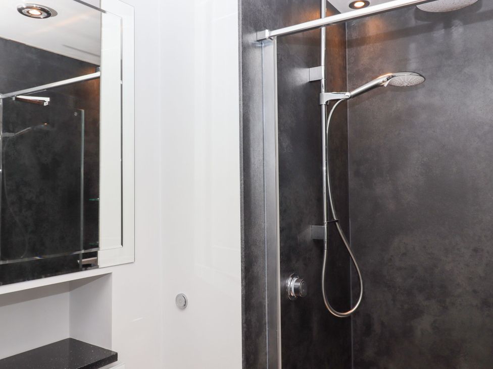 A shower with a mirror and sink in a bathroom at 15 Summerland Avenue Dawlish