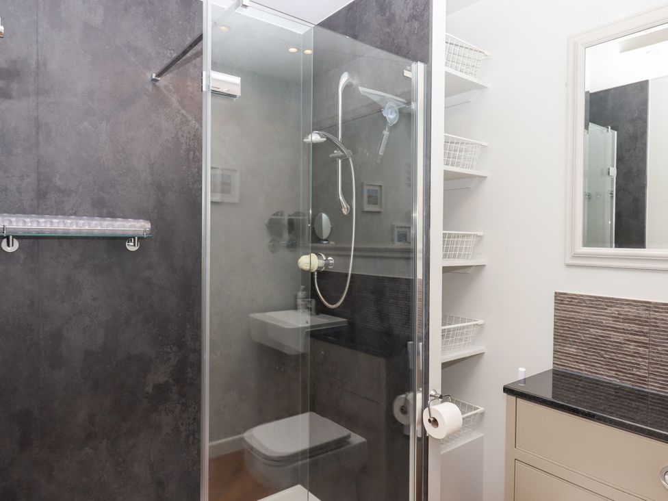 A bathroom with a shower, toilet, sink, and storage at 15 Summerland Avenue Dawlish